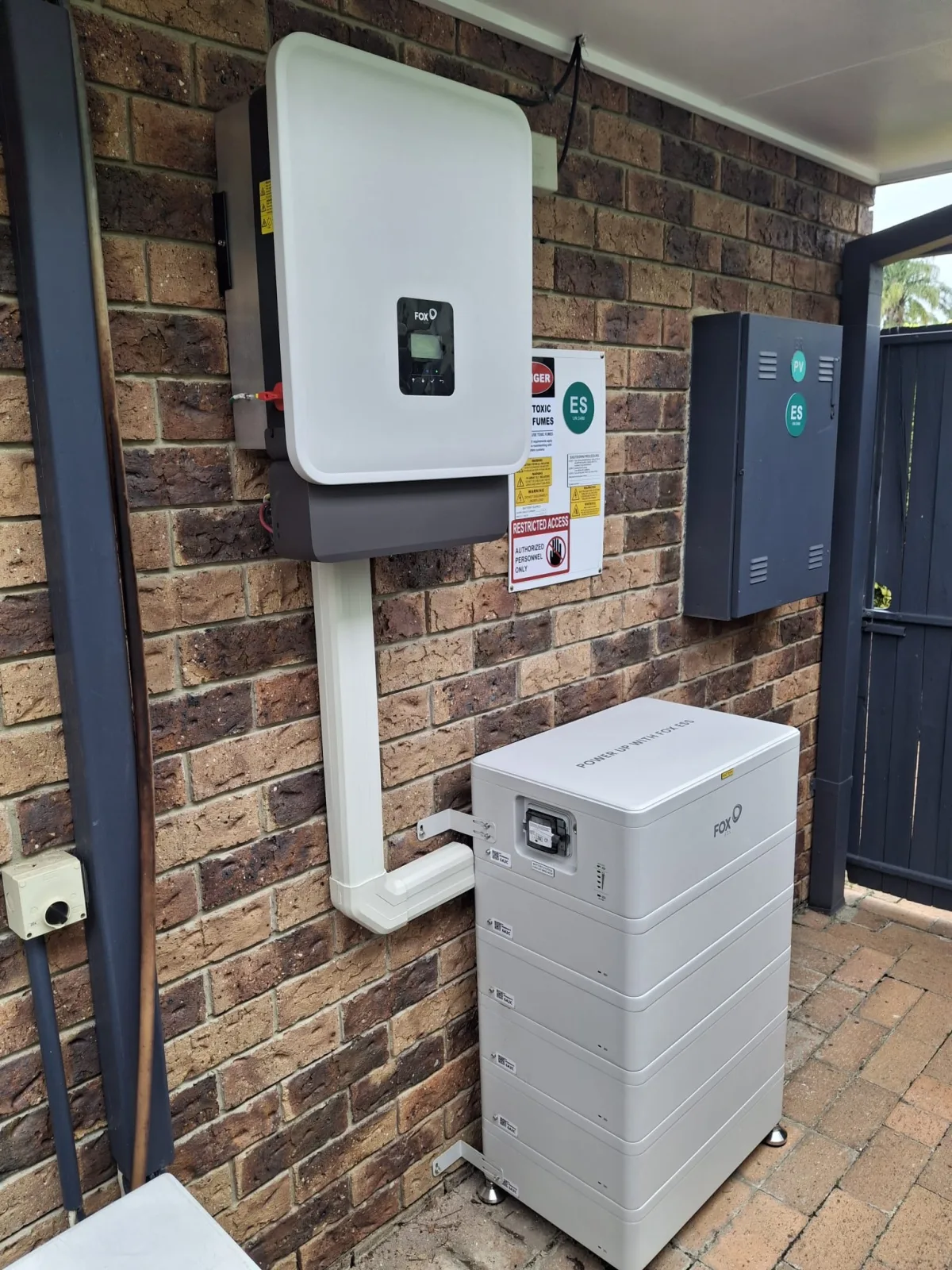 FoxESS EQ4800 battery installed on a brick wall with protected cable routing and support feet